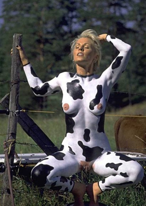 woman in cow makeup sitting naked by fence